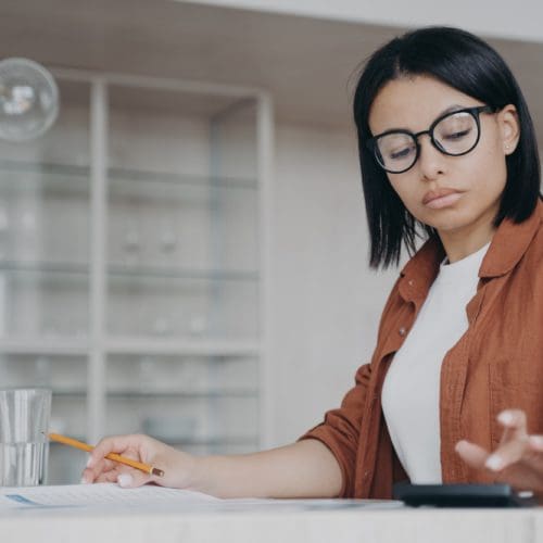 - Renewable Energy | Bear Atlantic Group Focused female in glasses counts expenses on calculator, managing project budget, sitting at desk